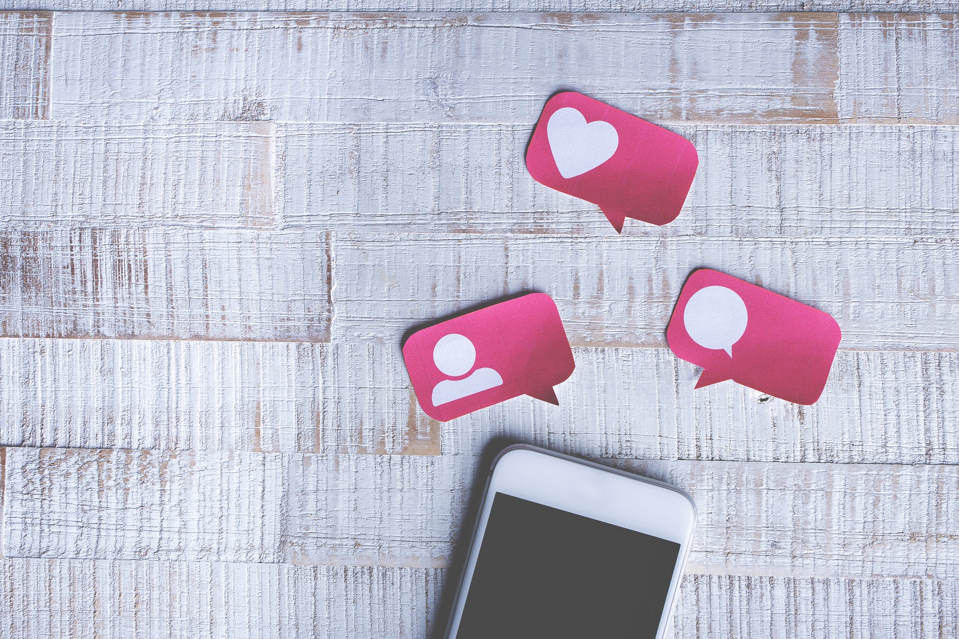 Cell phone on desk with social media likes and hearts icons