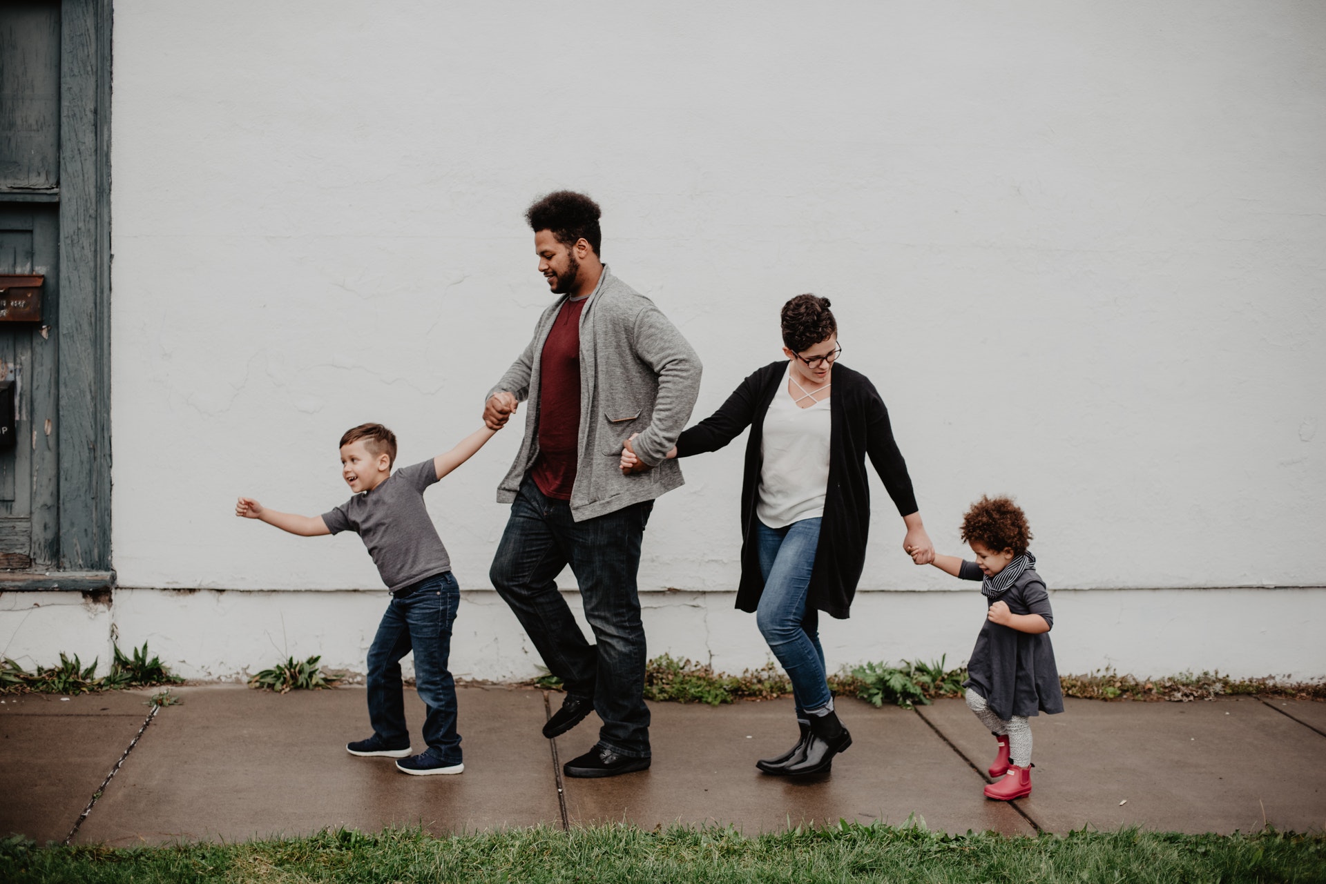 Family of four walking down the street holding hands and smiling