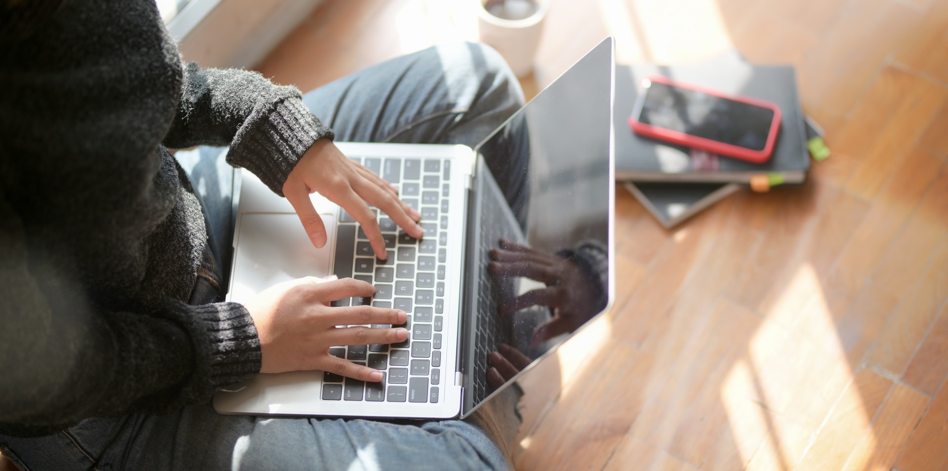 Female student sitting on floor studying real estate prelicensing online