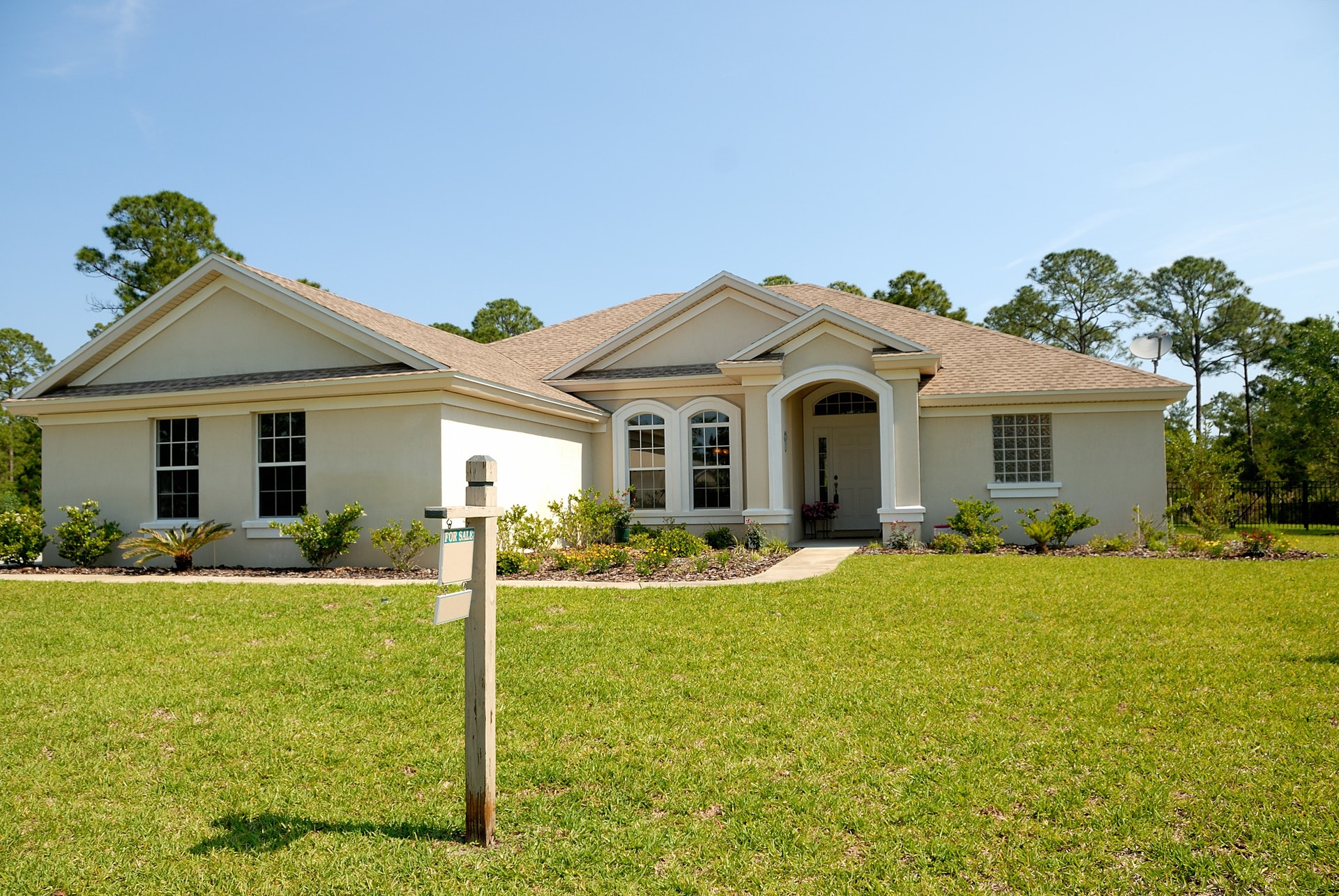 For sale sign in front of white and brown bungalow house