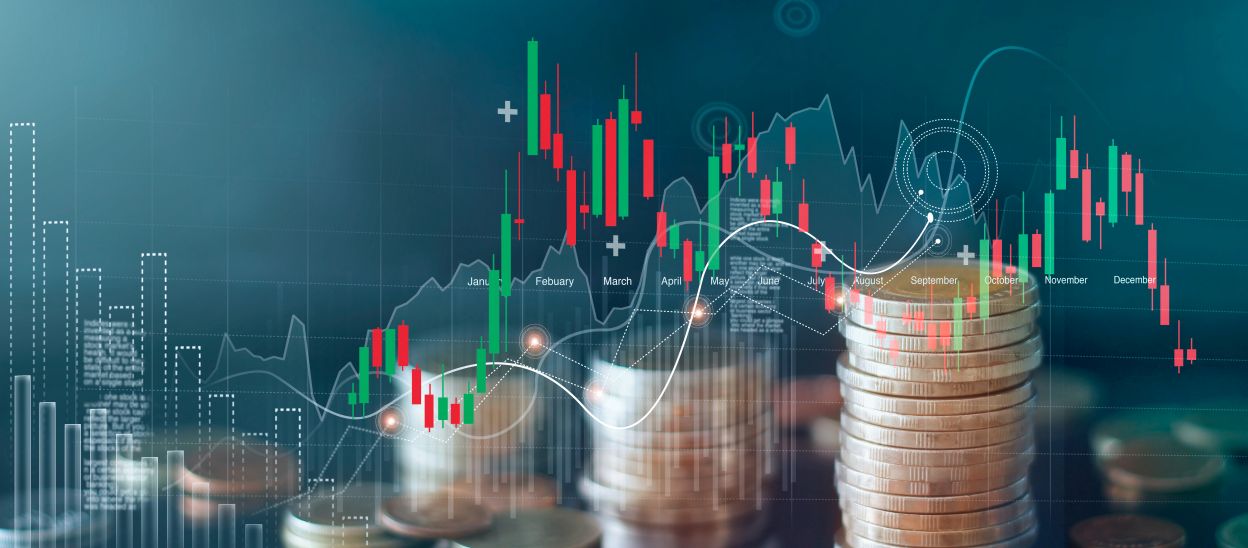 Foreign currency coins stacked on table in front of market analysis charts