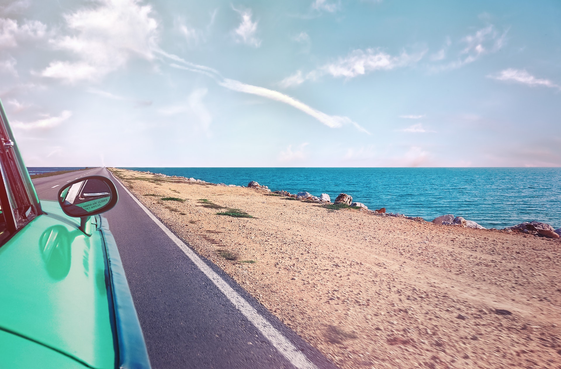 Green car driving along the coast