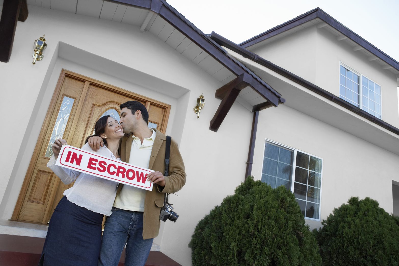 Home buyers standing in front of house that is in escrow