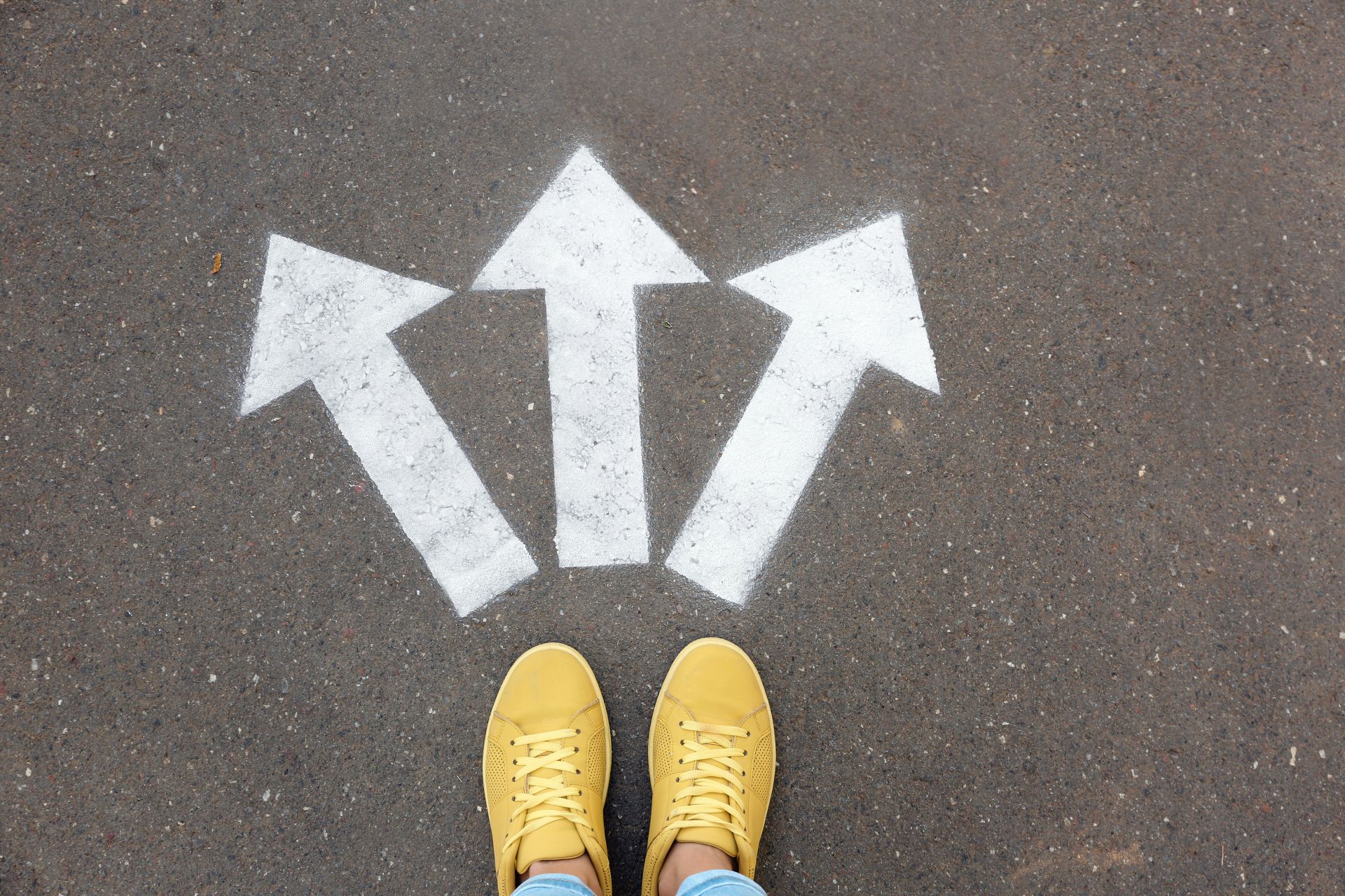 Person looking at three arrows painted on ground pointing to different paths