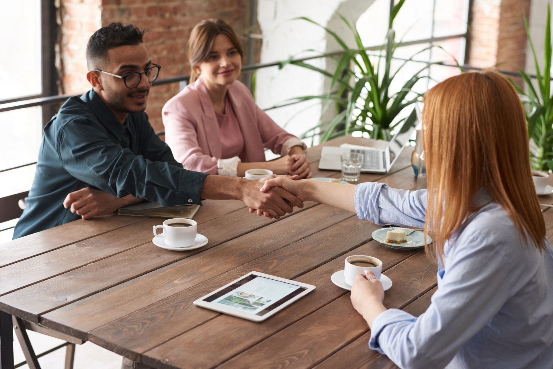 Realtor shaking hands with client over coffee