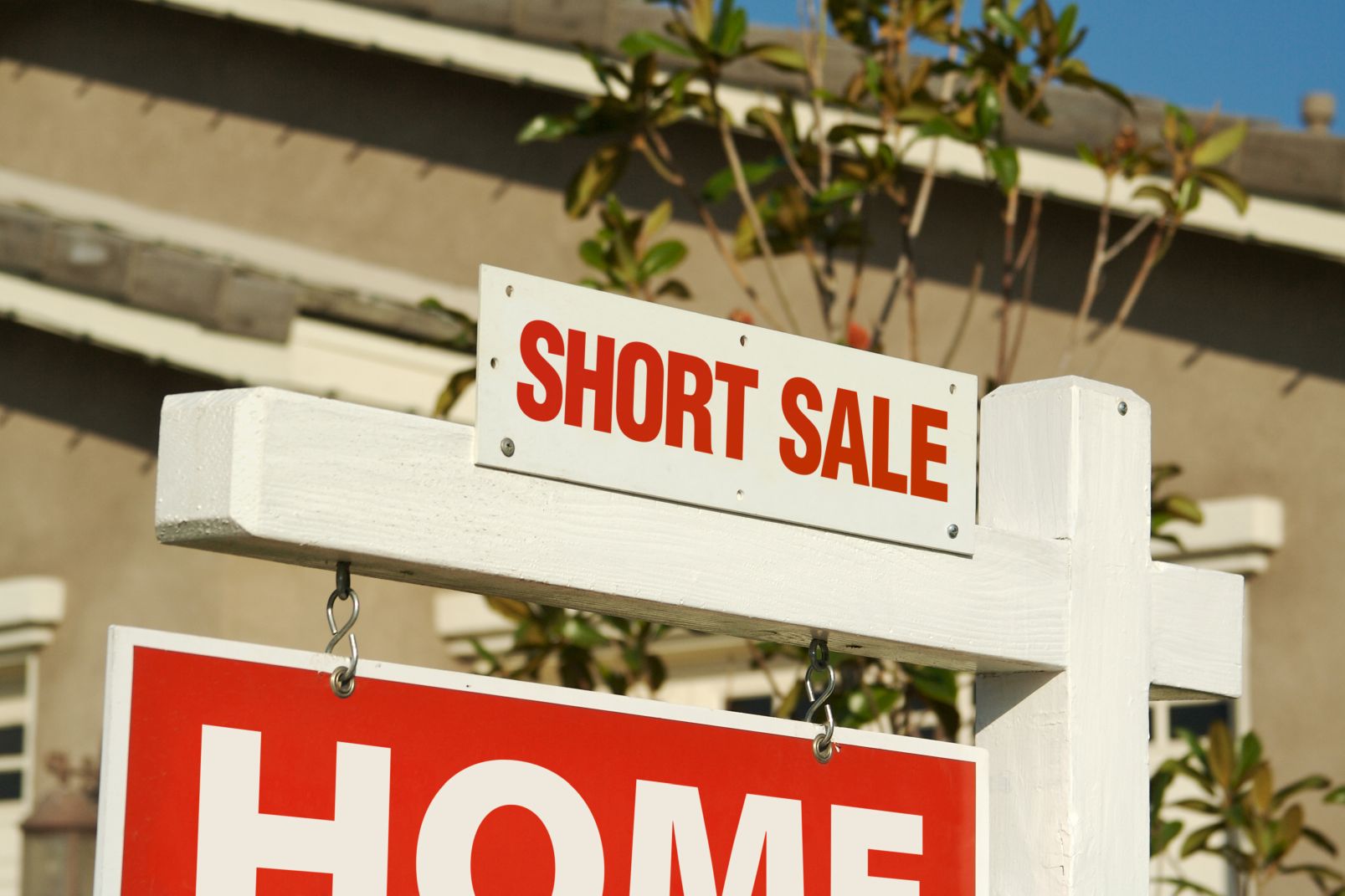 Short sale sign on top of for sale sign outside of home