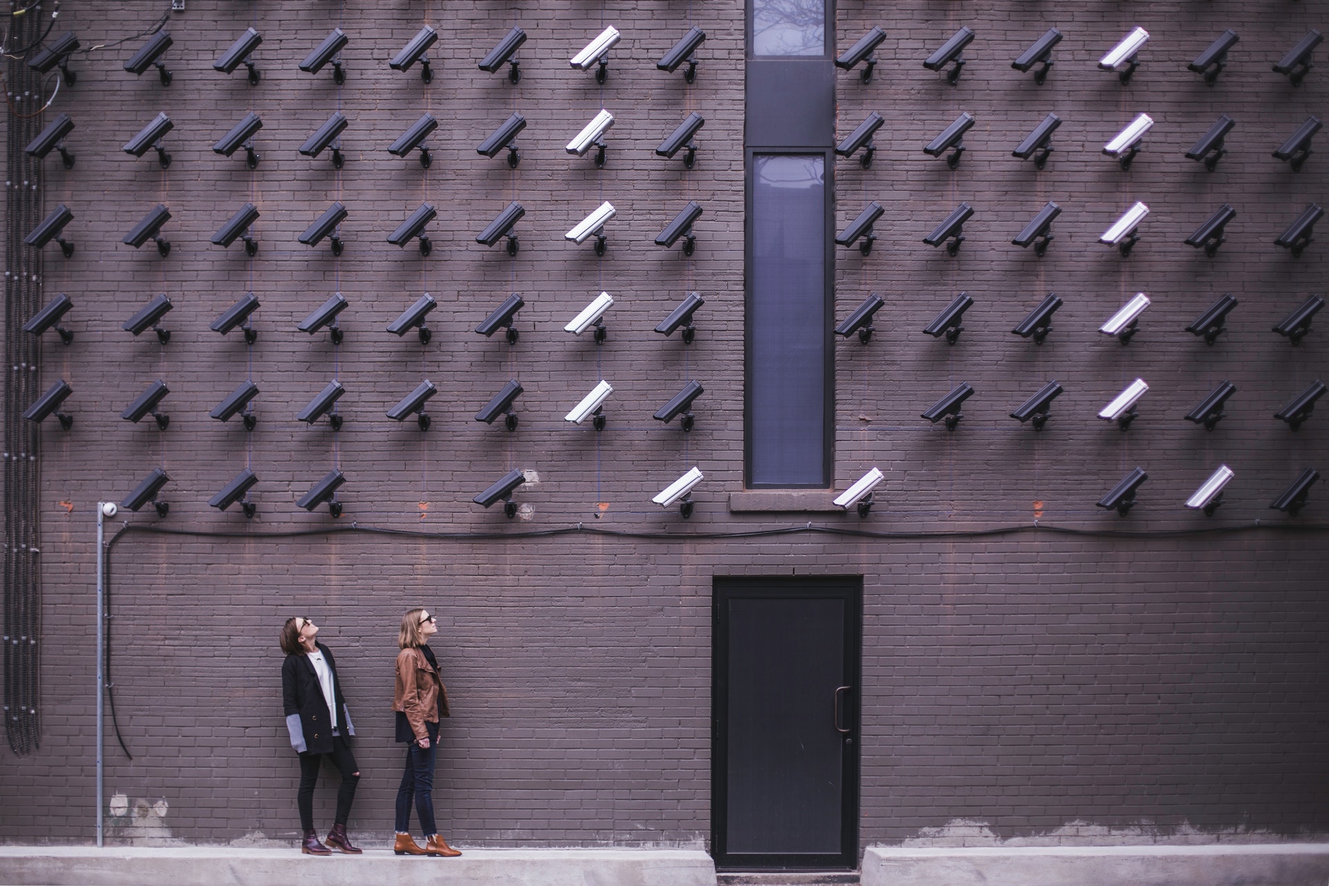 Surveillance cameras on building wall pointed at wo people